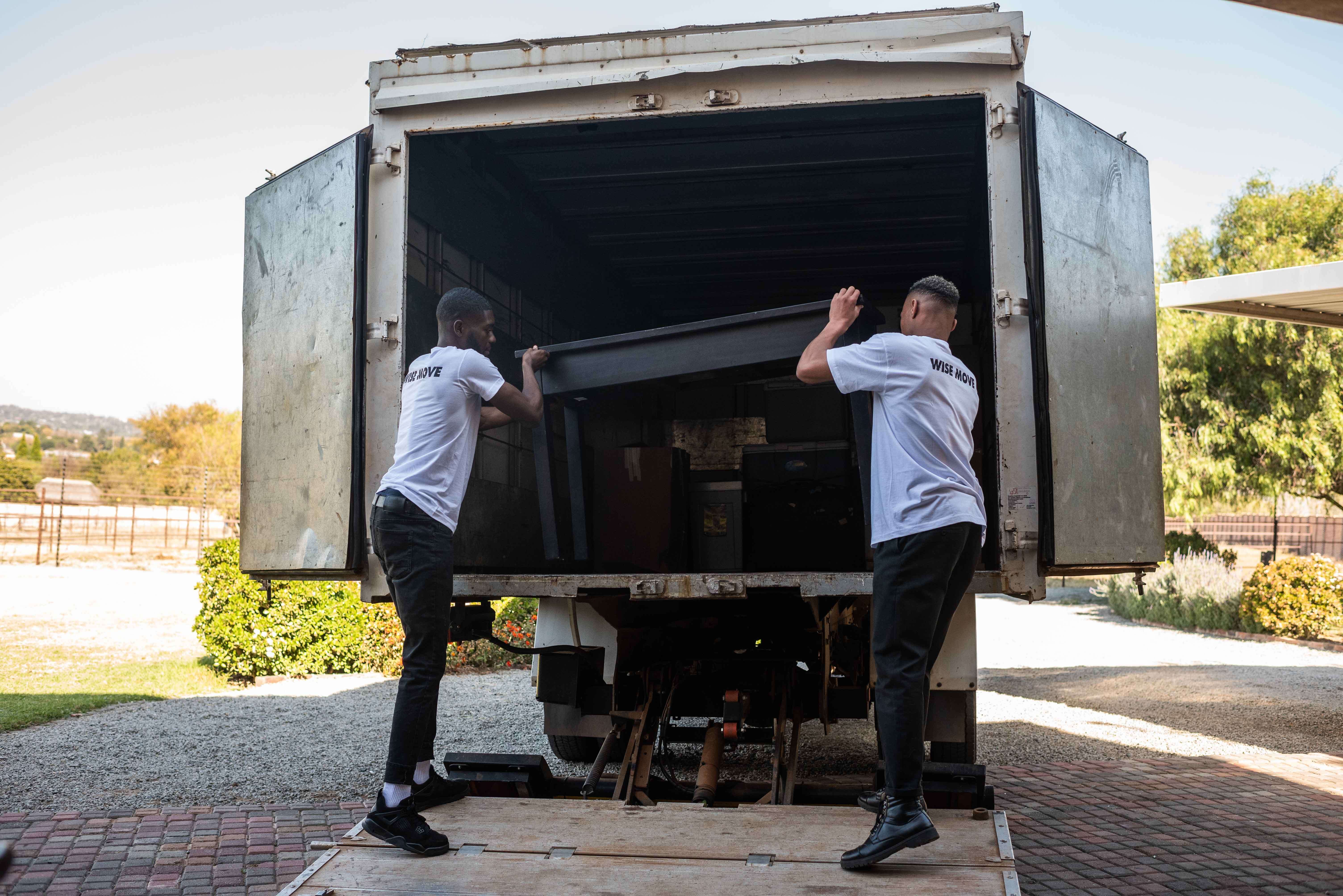 Two man are helping with removal to other place so they packing up stuff to the car.